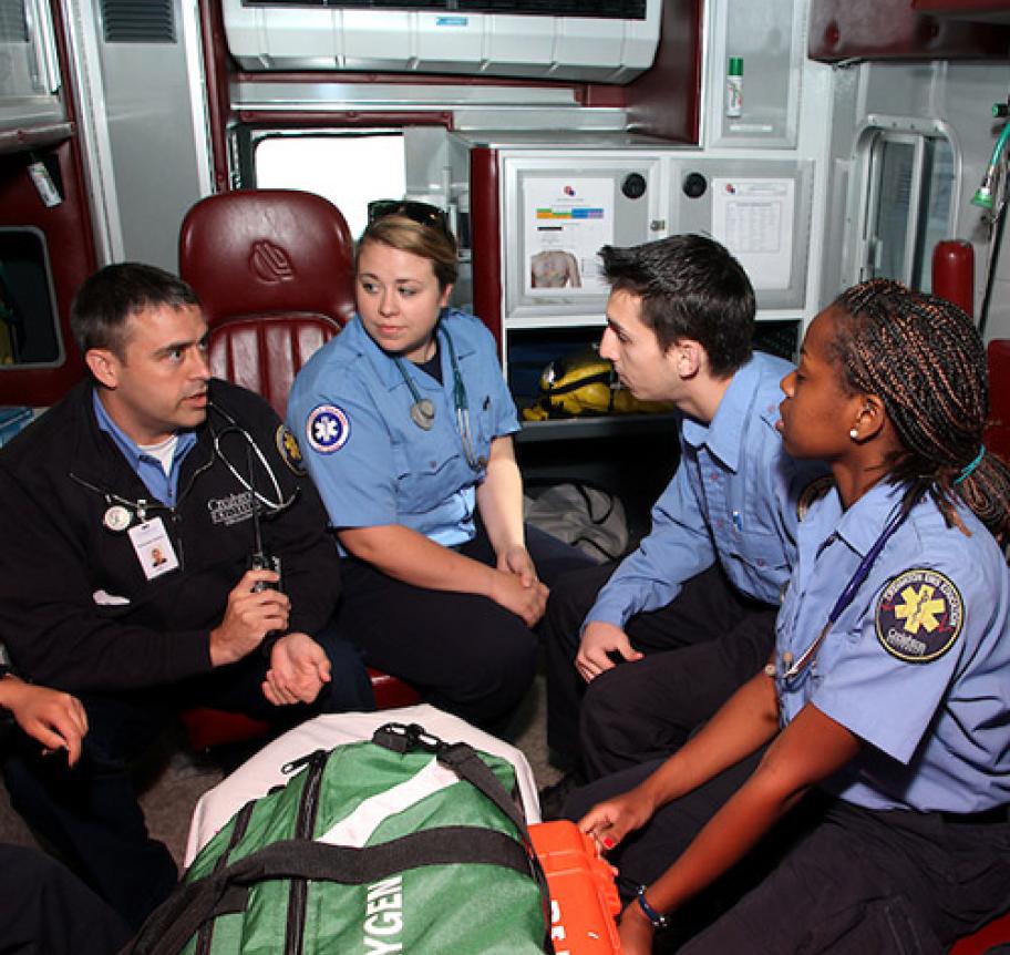 Paramedic students listening to their instructor in the back of an ambulance