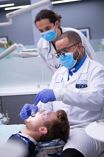 Samuels assisting students while working on dental patient.