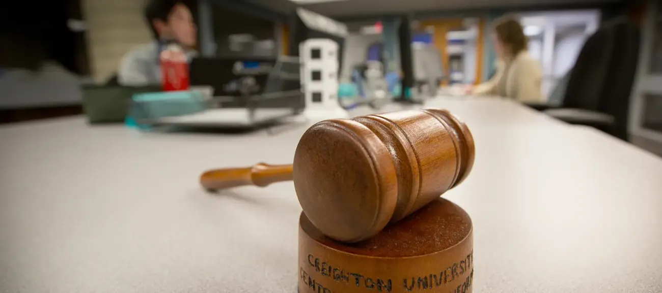 Picture of gavel on a table with people talking