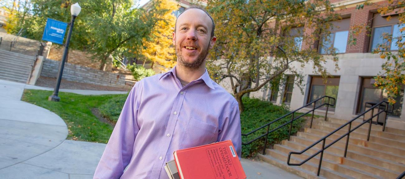 Andrew hogan holding his books on Creighton campus.