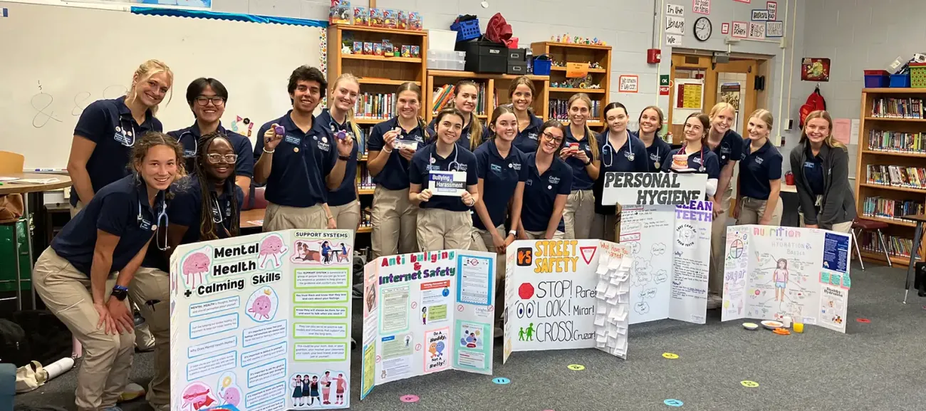 Many students in group hlding info posters.