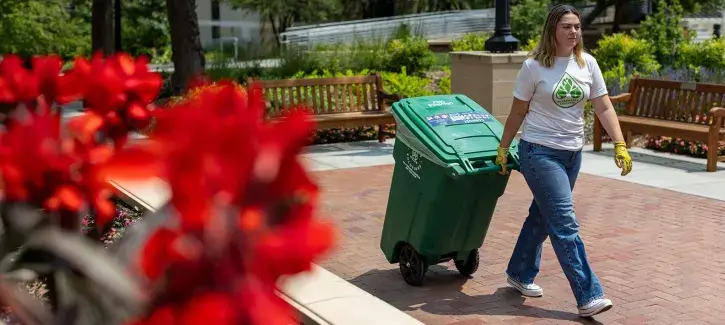 Student wheeling garbage barrel.