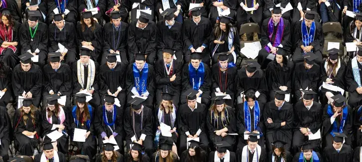 Students sitting for commencement in regalia.