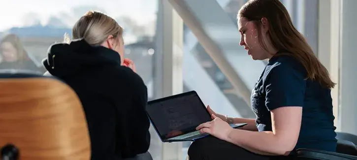 Two women talking while sitting in chairs in front of window