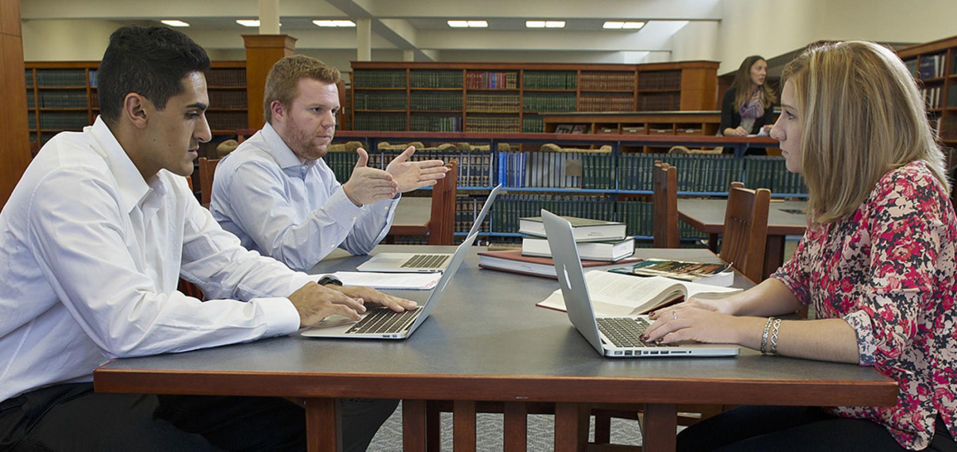 Two men talking at desk in law library