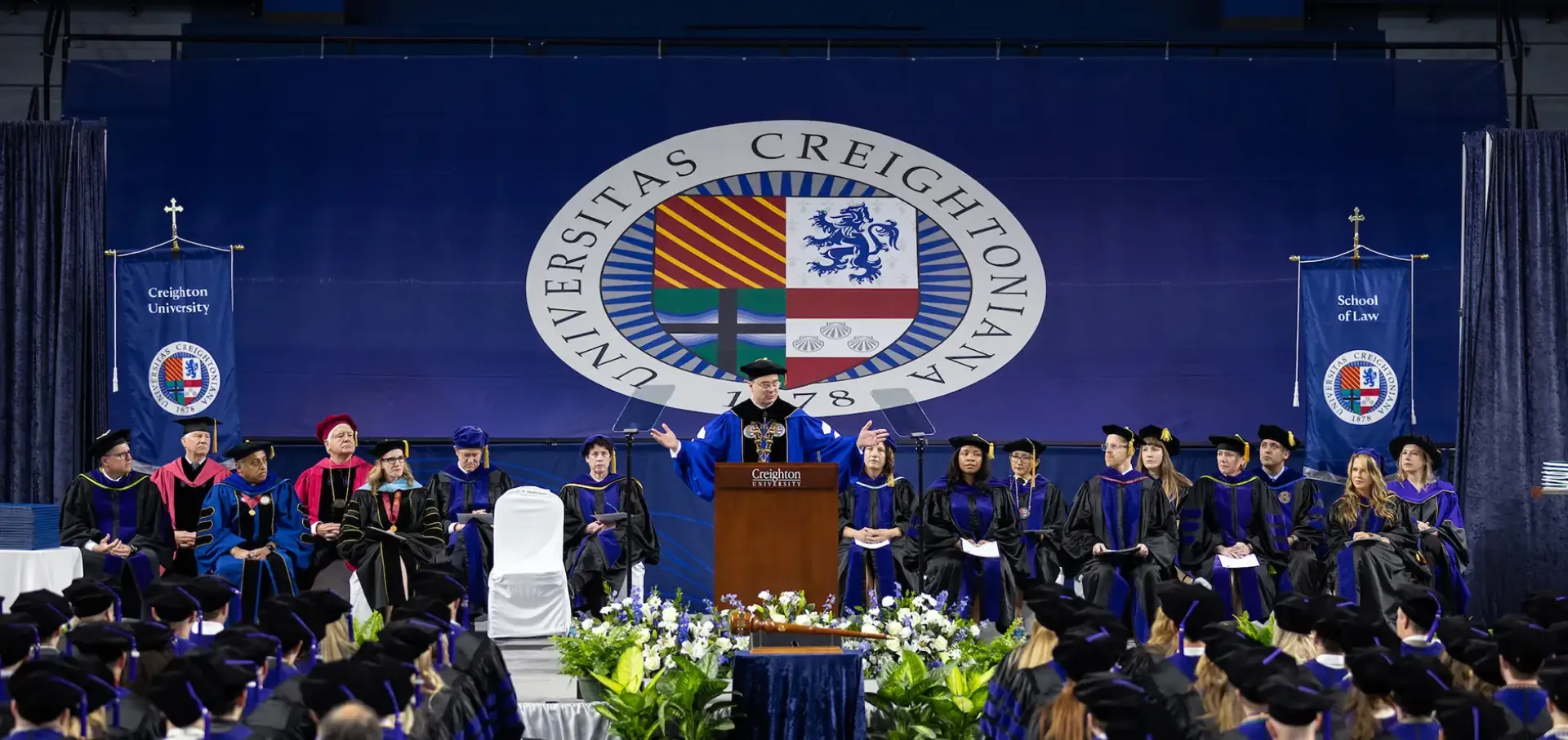 Law commencement with President Father Hendrickson addressing crowd.