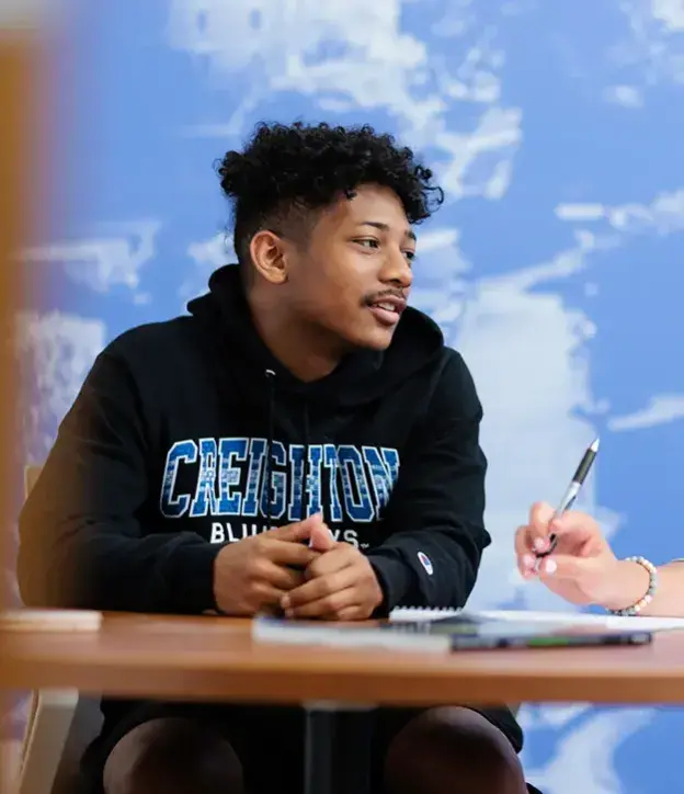 Creighton student with little fluffy clouds behind him.