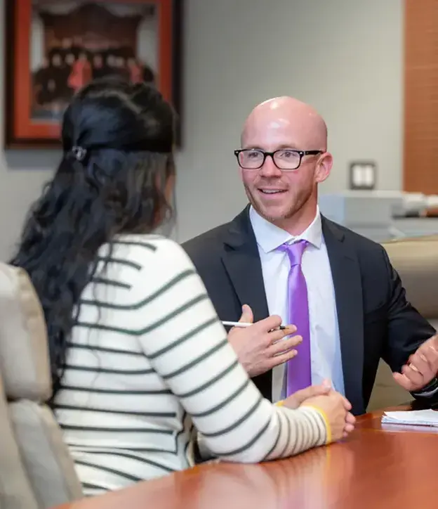 Two people talking at conference table.