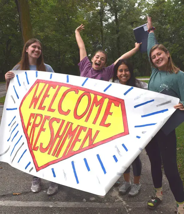 Students with banner welcoming freshmen.