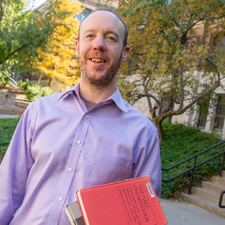 Andrew hogan holding his books on Creighton campus.