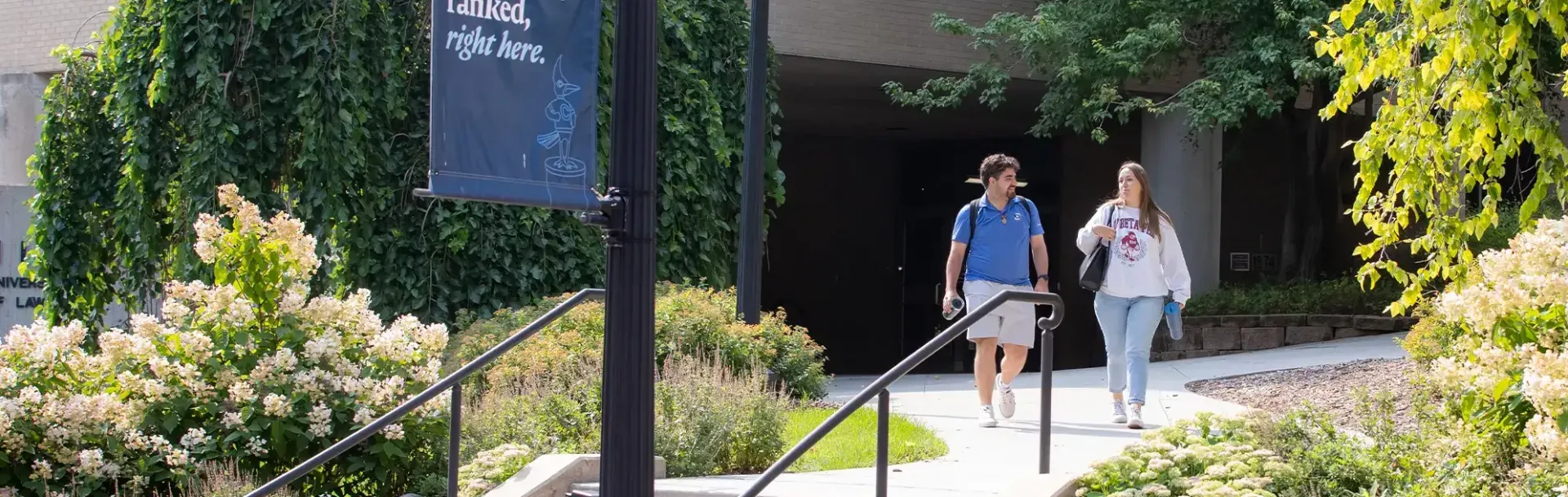 Two students walking near Law School building entrance.