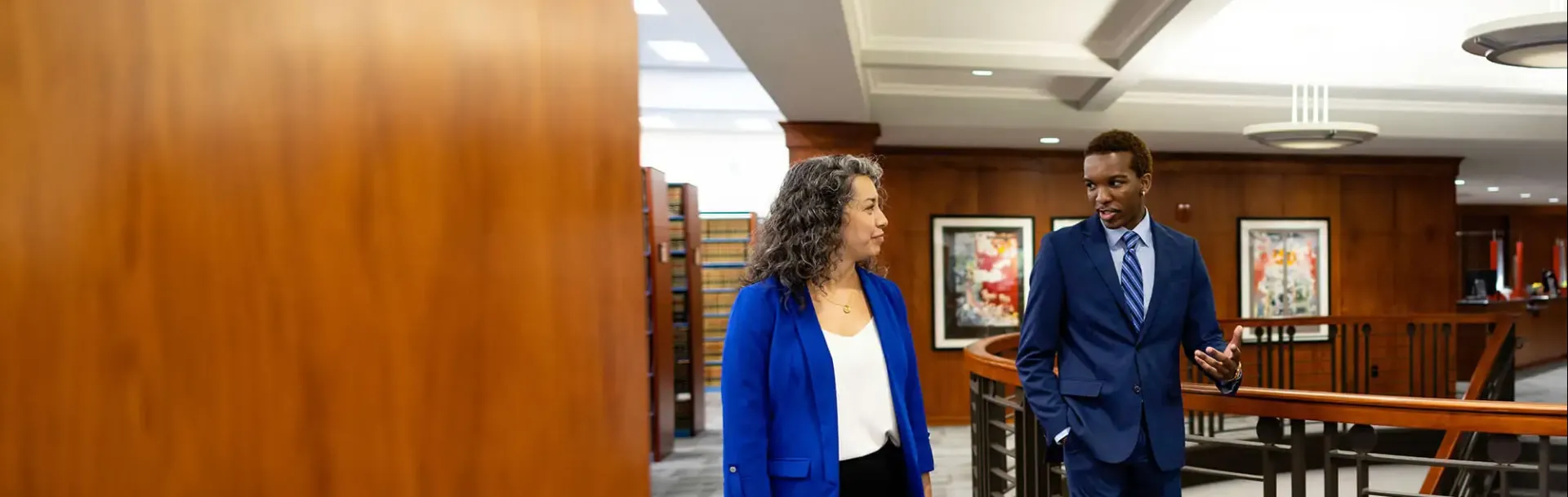 Two people walking and talking in law setting.