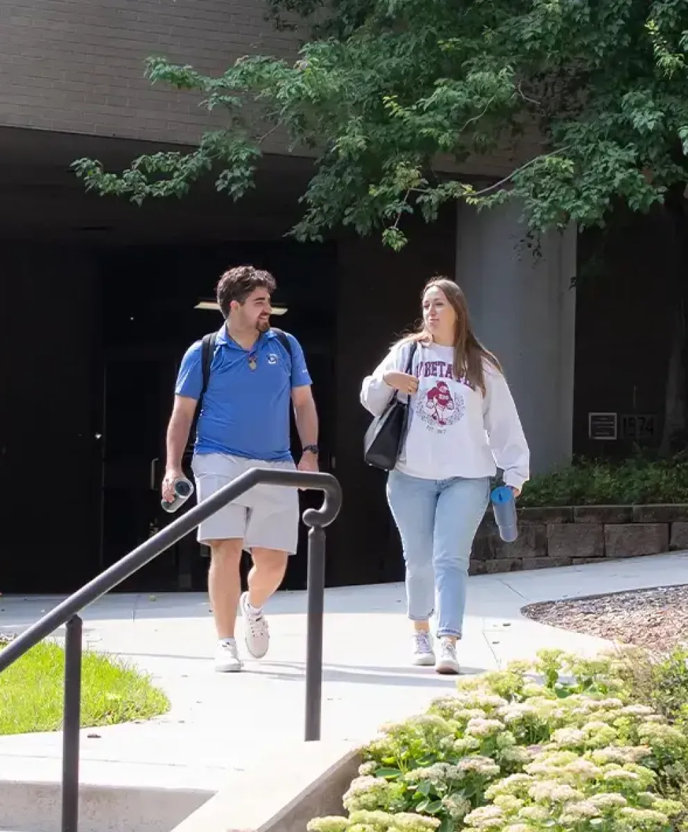 Two students walking near Law School building entrance.