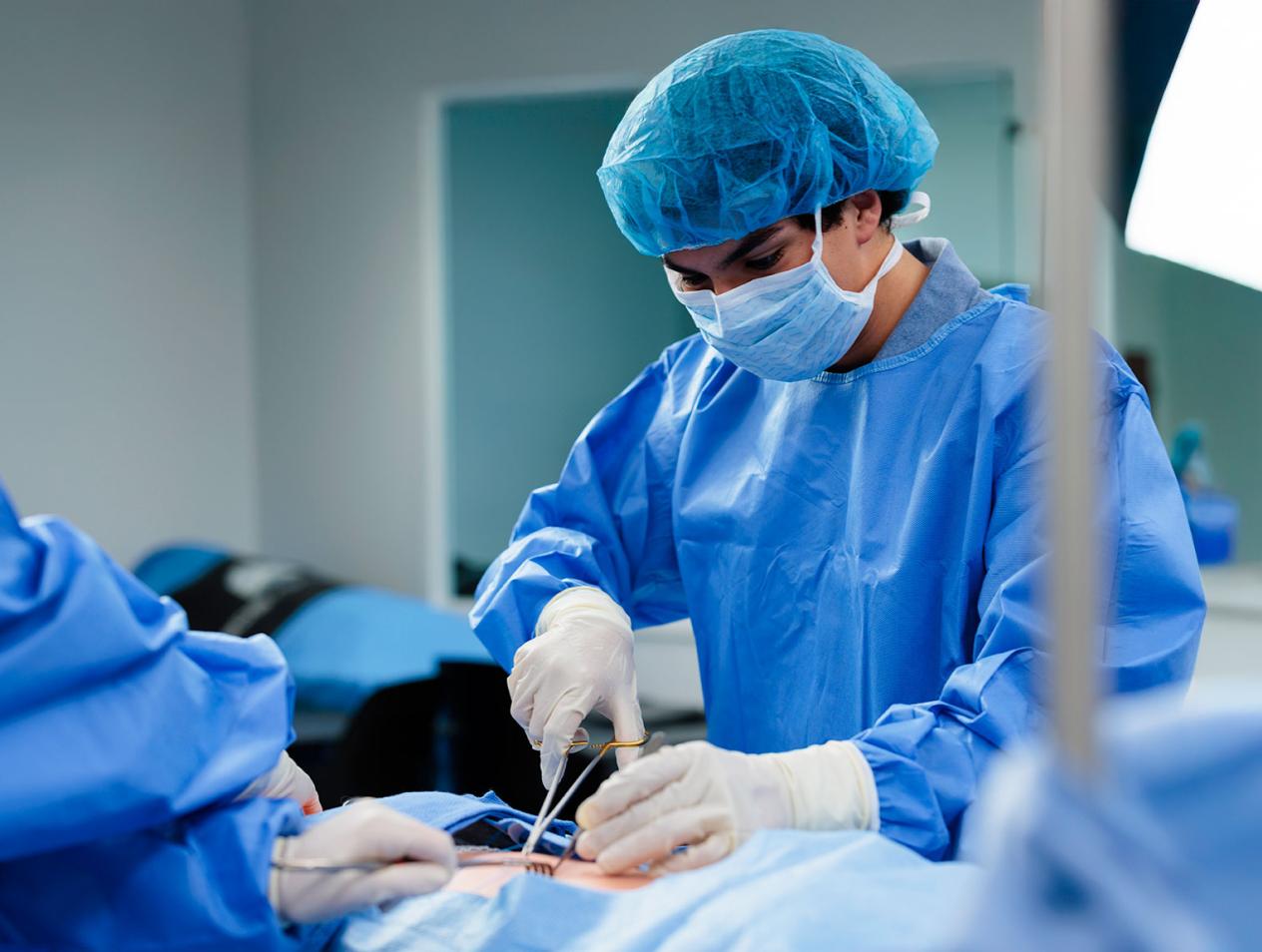 Student in blue scrubs performing a surgery procedure