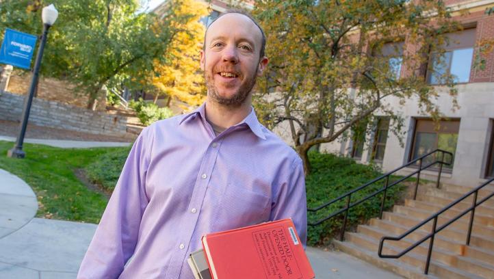 Andrew hogan holding his books on Creighton campus.