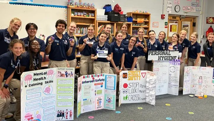 Many students in group hlding info posters.