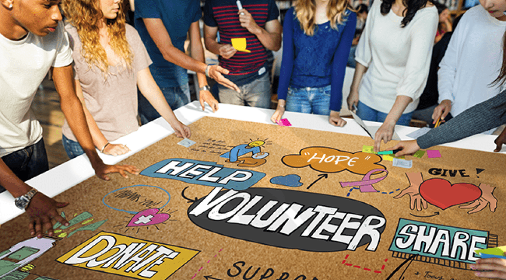 group of kids with a volunteer sign