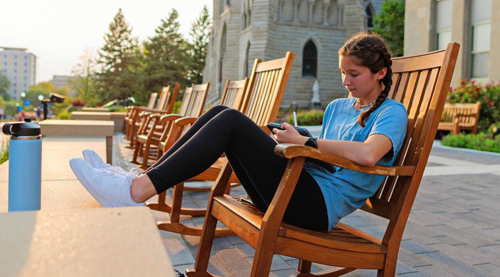 Student studying on rocking chair outdoors at sunset