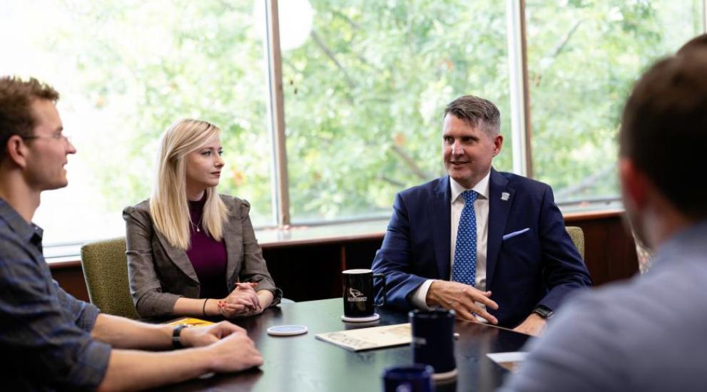 Faculty and students at a table. 