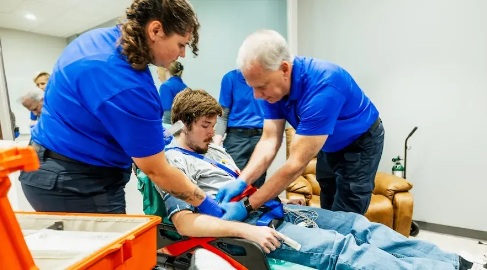 Paramedics working with man on stretcher.