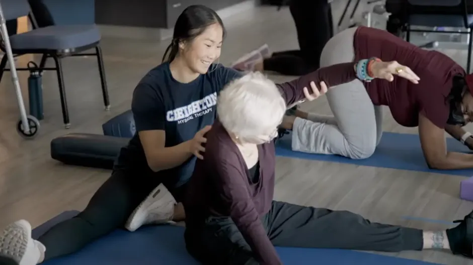 Therapist helping patient on floor mat with their arm movement.